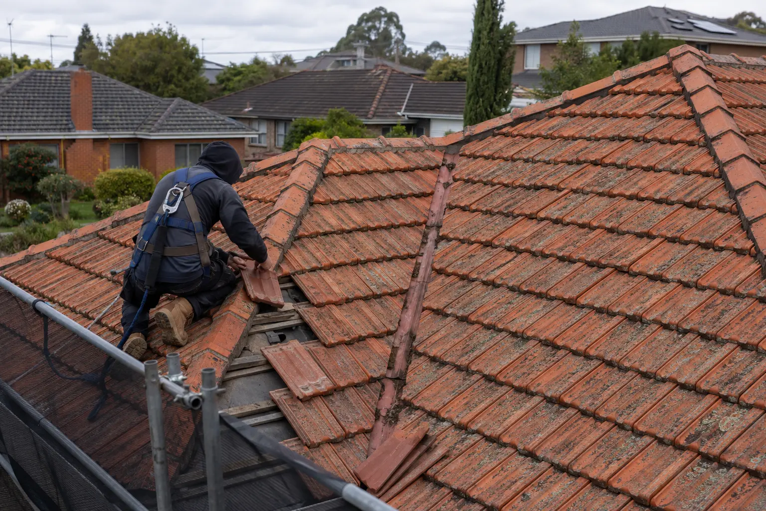 Concept image of a roofer repairing a suburban terracotta roof
